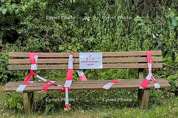 Blocked park bench with barrier tape and warning sign about oak procession spinners, Guxhagen, Hesse, Germany [IBR125180390]