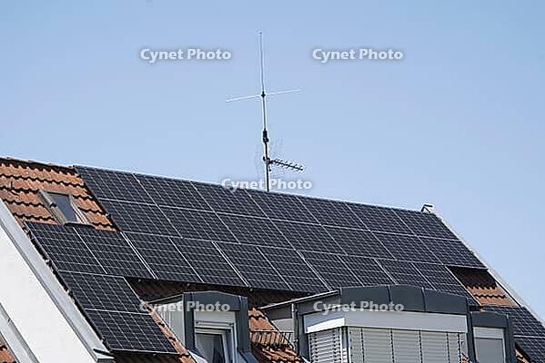 A residential building roof with solar panels. Clear blue sky with sunshine guarantees high electricity production. Dormer Windows and Skylights Provide More Light in the Attic Apartments [IBR125185851]