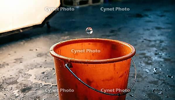 Single orange industrial safety bucket on dark concrete floor, single water droplet suspended mid-fall above bucket rim, inadequate response to industrial fire suppression system leak in chemical warehouse, safety concept, studio shot, AI generated [IBR125200685]