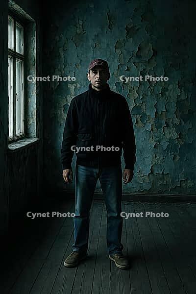 A solitary figure poses in a dim, worn-out room with peeling walls and a window, evoking a moody vibe, AI generated [IBR125203208]
