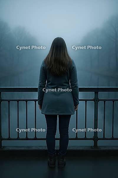 A woman faces a fog-covered body of water, leaning on a railing in a reflective, solitary, winter landscape, AI generated [IBR125203219]
