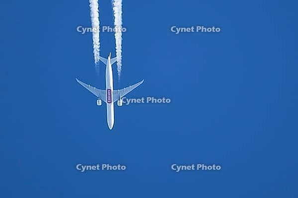 Boeing 777 jet passenger aircraft of Emirates airlines flying in a blue sky with contrails or vapour trails behind in the atmosphere, England, United Kingdom [IBR125204145]