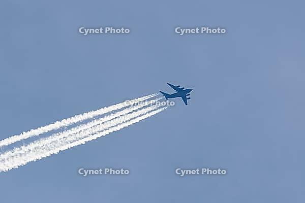 Boeing C-17 Globemaster III military jet aircraft of the United States Air Force USAF flying in a blue sky with contrails or vapour trails behind in the atmosphere, England, United Kingdom [IBR125204146]