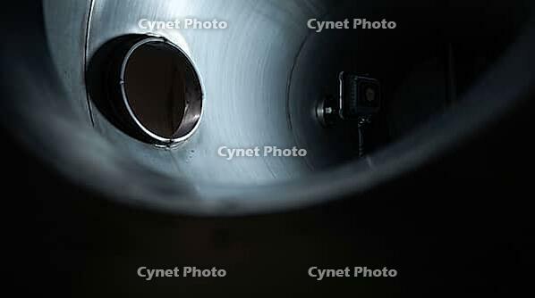 Portable magnetic work light on interior wall of dark industrial vessel, viewed through manway opening, chemical plant, AI generated [IBR125211485]