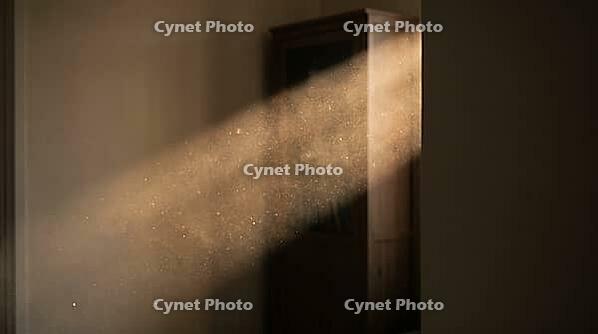 Sunbeam cutting through a dim living room revealing suspended particulate haze, indoor wildfire smoke contamination concept, AI generated [IBR125211541]