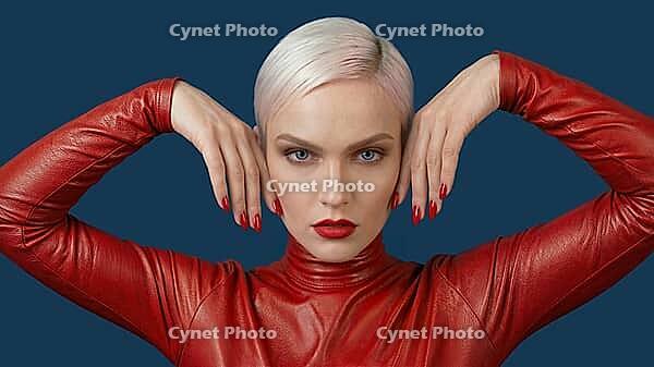 Woman with short platinum blond hair wearing a red leather outfit against a blue background. Red fingernail polish, AI generated [IBR125237526]