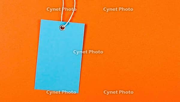 Blue label on a string against a bright orange background. Copy space. Graphic resource, AI generated [IBR125237544]