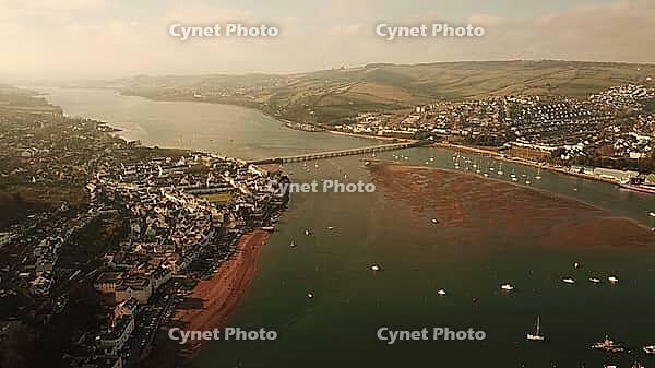 Aerial view of a river estuary, village, and surrounding green hills with bridges and boats, Teignmouth, Devon, UK [IBR125242397]