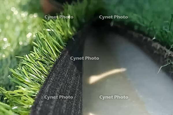 Spreading artificial turf in the stadium, rolling out rolls of lawn and leveling [IBR125242444]