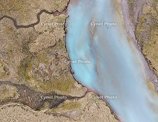An aerial view of a glacial river braiding across Iceland's volcanic sandur plain, its milky turquoise water fed by meltwater from a nearby glacier, Iceland [IBR125242445]