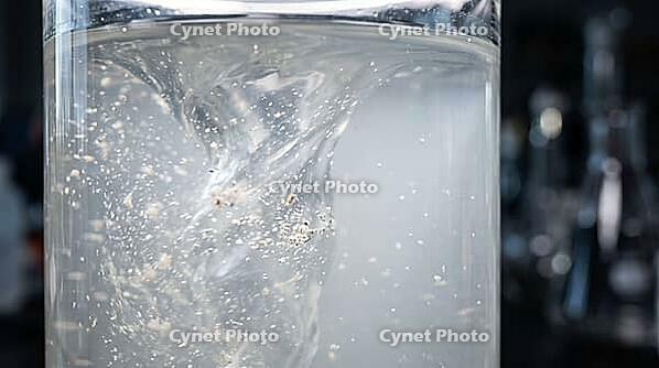 Abstract macro of a cloudy wash buffer solution with suspended particles swirling mid-process, laboratory sample extraction, studio shot, AI generated [IBR125242484]