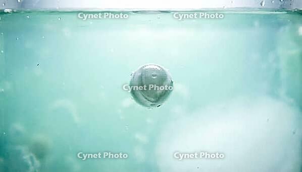 Abstract macro of a pale green-blue chlorine wash solution with an unaffected spherical particle suspended within it, food safety chemistry concept, studio shot, AI generated [IBR125242487]