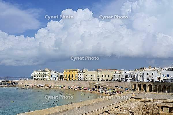 The coast of Gallipoli with lots of people relaxing on the beach and white and yellow buildings [IBR125261574]