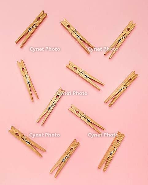 Wooden clothes pins on a pink background [IBR125280322]