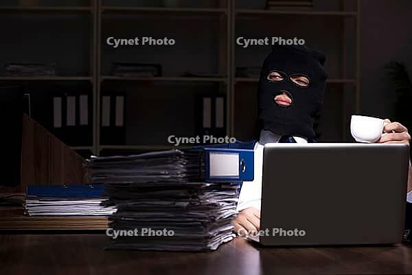 The male employee steals information in the office at night [IBR125304688]