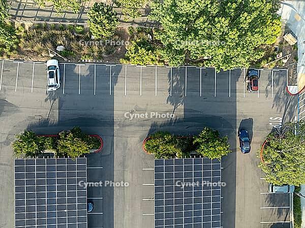 Aerial view of solar panels installed as shade roof over parking lot for parked cars. Photovoltaic technology integrated in urban infrastructure. [IBR125324055]