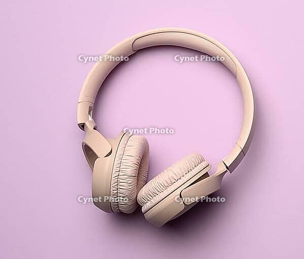 Beige wireless headphones on a purple background. Top view on modern gadget [IBR125331124]