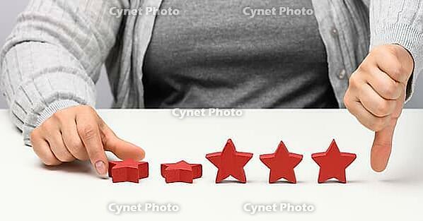 Customer experience feedback concept. Red stars, poor rating about services with a female hand. White table [IBR125331126]