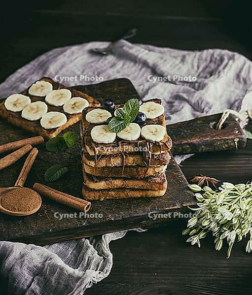 Square French toasts of white bread with chocolate and pieces of banana on a wooden board, vintage toning [IBR125331129]