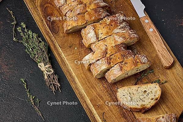 Sliced ??baguette with flax and spices on a wooden cutting board. Top view [IBR125331135]