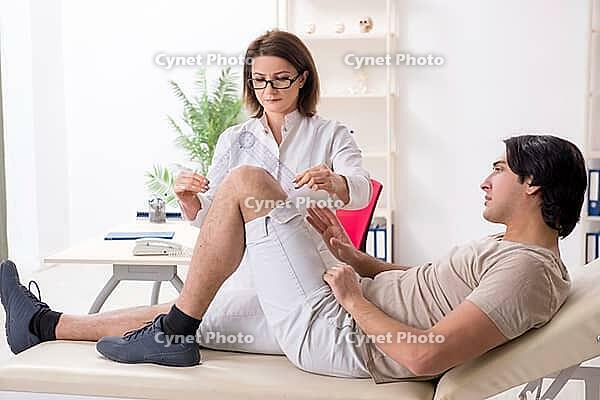 The doctor checks the patient's joint flexibility with a goniometer [IBR125331150]
