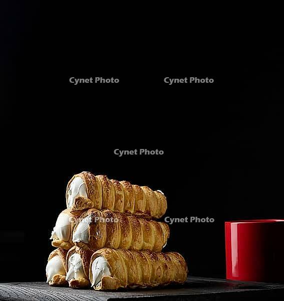 Baked tubules filled with whipped egg whites cream on a black wooden kitchen board [IBR125331160]