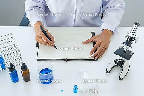 Scientists researching in laboratory in white lab coat, gloves analysing, looking at test tubes sample, biotechnology concept [IBR125331166]