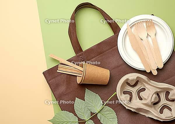 Disposable paper utensils from brown craft paper and recycled materials on a green background, plastic rejection concept, zero waste [IBR125331192]