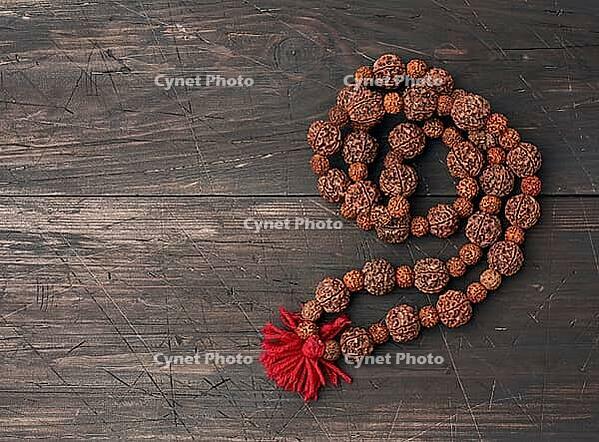 Rudraksha prayer beads for meditation on a brown wooden background, top view. Japa mala, copy space [IBR125331199]
