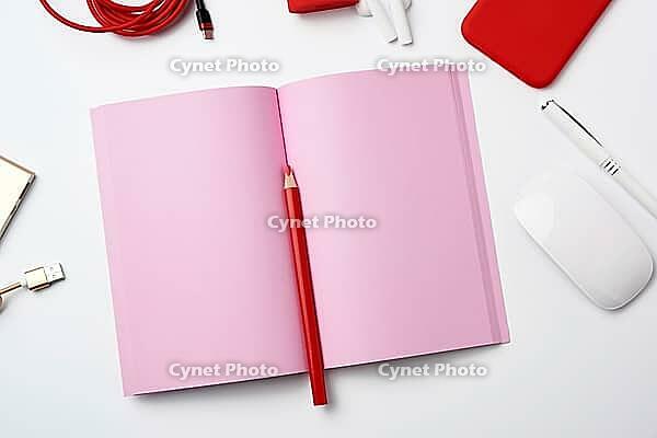 Open pink paper notebook, power bank with cable, red smartphone, headphones, wireless mouse on white background, workplace, top view, flat lay [IBR125344234]
