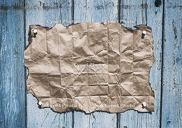Brown kraft paper with burnt edges on an old cracked wall [IBR125344248]