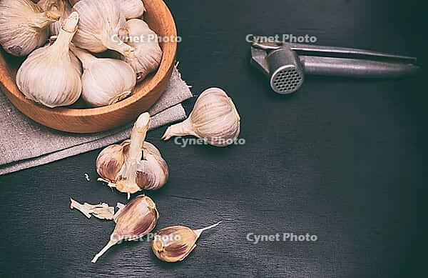 Fruit of garlic in a wooden bowl and on a table, black wooden background [IBR125344251]