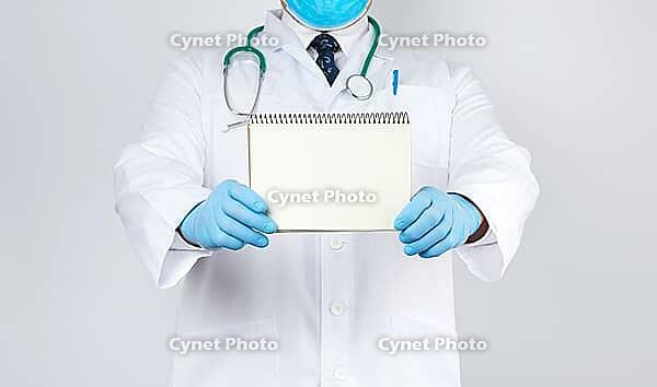 Male doctor in a white coat and medical blue gloves holds a notebook with blank white sheets on a white background, place for an inscription [IBR125344268]