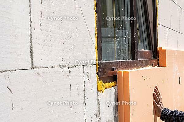 An der Gebäudewand befestigte Schaumstoffplatten-Dämmung, thermische Sanierung, energiesparende Fassade, moderne Verkleidung, Montageverfahren, Bauarbeiten vor Ort, Anbringung [IBR125344278]