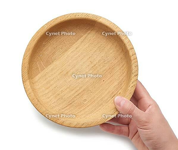 Hand holds an empty brown wooden plate on a white isolated background, top view [IBR125344283]