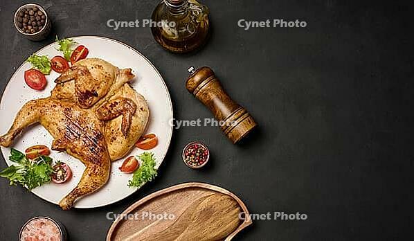 Whole fried chicken with spices in a white round plate on the table, top view. Copy space [IBR125344305]