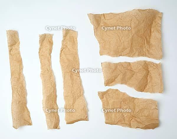 Torn brown pieces of parchment paper on a white background, flat lay [IBR125344318]