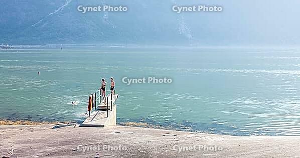 Kids swimming and jumping in cool fjord water, having fun, Eidfjord, Norway [IBR113372473]