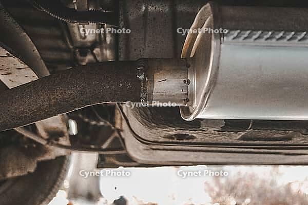 An aftermarket exhaust muffler installed on an older vehicle with signs of welding. automotive element [IBR125363537]