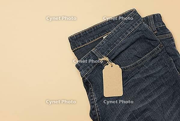 Blank cardboard rectangular tag tied to blue jeans. Top view, copy space [IBR125363538]