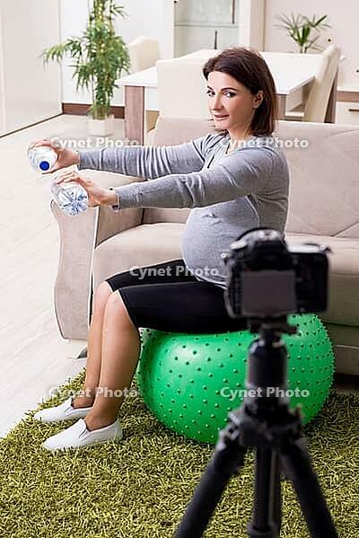 Pregnant blogger doing physical exercises [IBR125363578]
