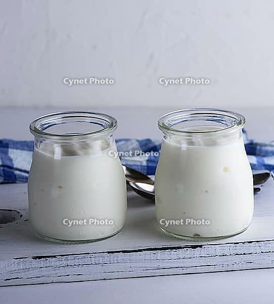 Homemade yogurt in a glass jar on a white wooden board, close up [IBR125363584]