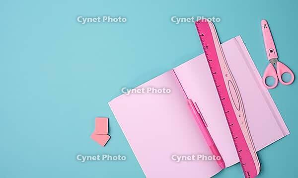 Open notebook with blank pink sheets, scissors and ruler on blue background, top view [IBR125363590]