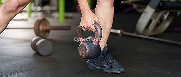 When lifting a kettlebell, a person shows the correct shape and emphasizes strength and fitness in a fitness atmosphere [IBR125363608]