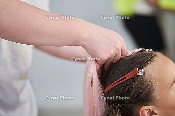 The beginning of braiding braids using pink kanekalon material. The hands of the master hold the material. With space to copy. [IBR125363616]
