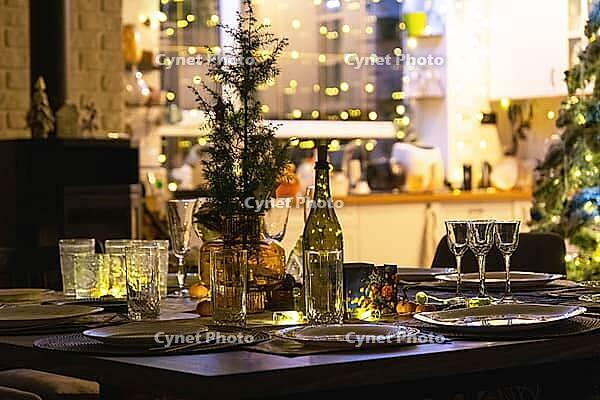 Festive interior of house is decorated for Christmas and New Year in loft style with black stove, fireplace, Christmas tree. Warm studio room with set table, burning wood, cozy and heating of home [IBR125382566]