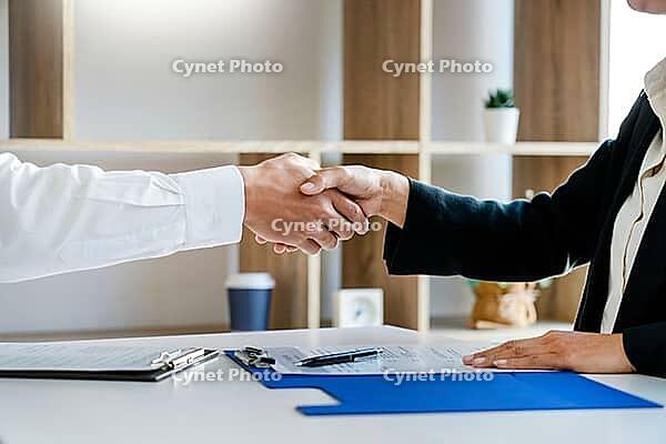 Businessman and businesswoman handshaking over the office desk after Greeting new colleague, business meetings concept [IBR125382578]