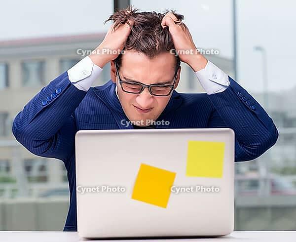 The workaholic businessman overworked with too much work in the office [IBR125382585]