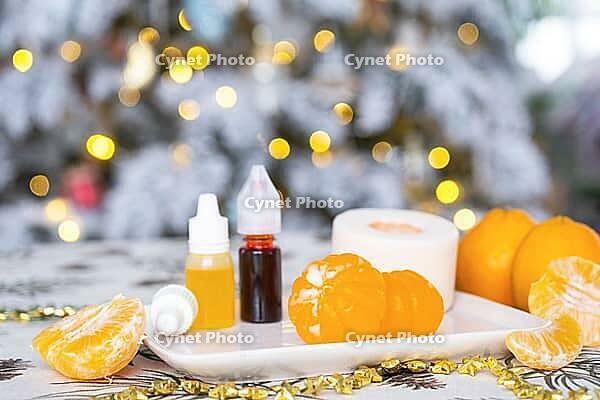 Handmade soap in the form of Orange tangerine with bottles of dye, flavor, a block of glycerin soap base, silicone mold, on background of Christmas tree with golden light. Soap as gift new year [IBR125382593]