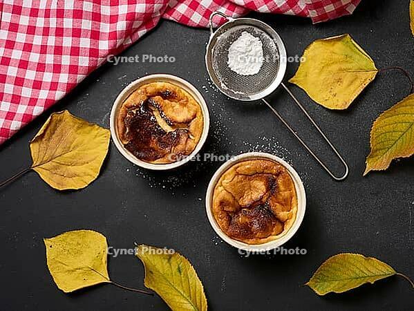 Cottage cheese dessert baked in portioned round ceramic plates on a wooden black table, top view [IBR125382600]